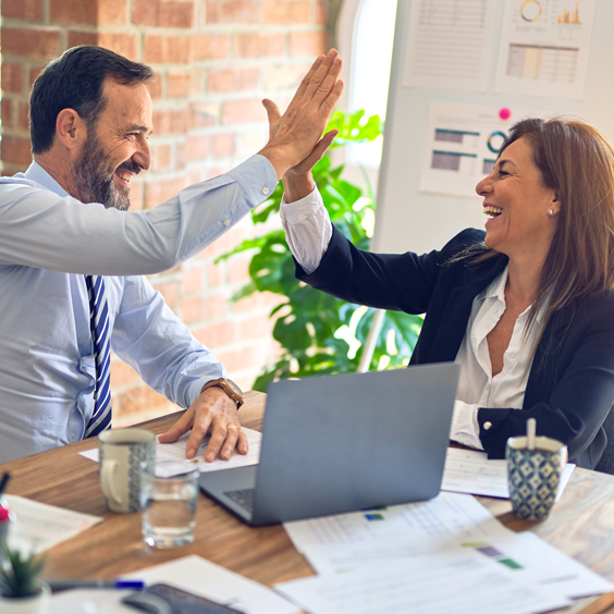 Business man and woman high fiving while working on a project